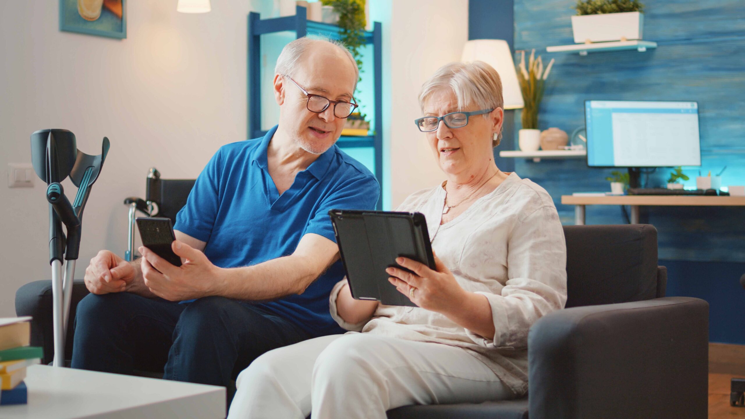 Elderly couple using a tablet and smartphone to access remote patient monitoring tools as part of a chronic care management program at home. 